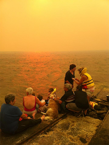Residents of Murdunna, Tasmania, take shelter at the town's boat ramp from a nearby blaze